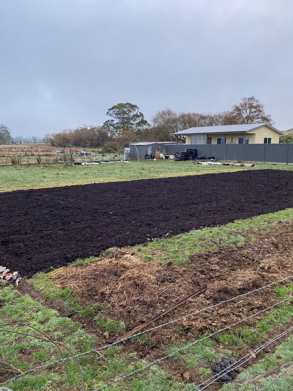A rural landscape with a fenced field, a house, and a tractor. - Cosy little farm stay (Bullarook)