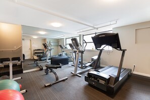 Une salle de sport équipée de tapis de course, de vélos elliptiques et de poids libres.