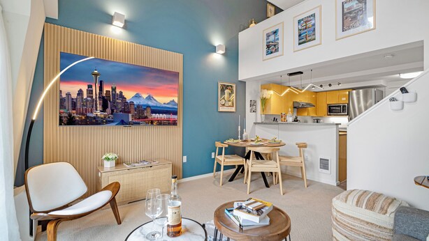 Uma sala de estar moderna com uma pintura de paisagem urbana, uma área de jantar com móveis de madeira e uma cozinha com eletrodomésticos de aço inoxidável.