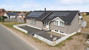 Une maison à deux étages, dotée de panneaux solaires sur le toit, d’une cour clôturée et d’une pancarte indiquant qu’il s’agit d’un bien locatif.