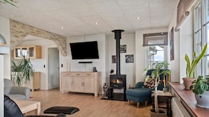 Un salon chaleureux avec une cheminée, un téléviseur et des fauteuils confortables.