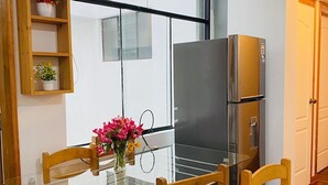 A modern kitchen with a glass dining table, wooden chairs, a stainless steel refrigerator, and a window with a view. - Relax in San Blas - 3-Bedroom Apartment with Views 🌅 (Cusco)