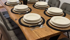 Une table à manger dressée avec des assiettes, des couverts et des sets de table.
