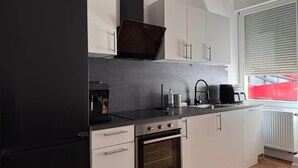 Une cuisine moderne avec un réfrigérateur noir, un four en acier inoxydable et une machine à café.