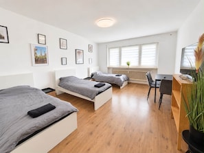 A modern hotel room with two single beds, a desk, a chair, and a television. - Wohnung Niedernhausen 6 Betten Stellplatz (Niedernhausen)