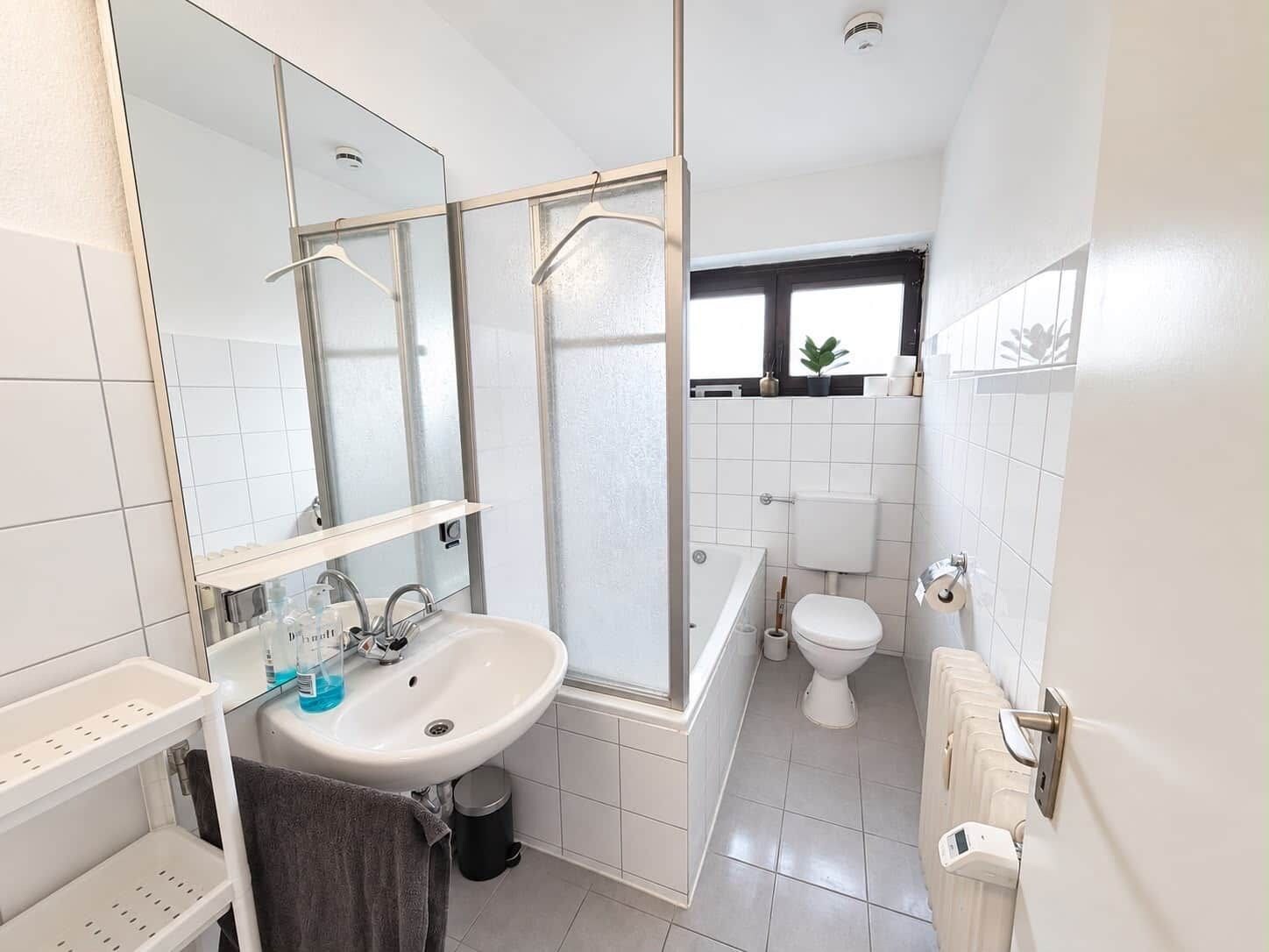 Ein modernes Badezimmer mit einem weißen Waschbecken, Spiegel und einer Toilette.