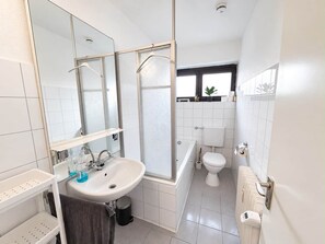 A modern bathroom with a white sink, mirror, and toilet. - Wohnung Niedernhausen 6 Betten Stellplatz (Niedernhausen)