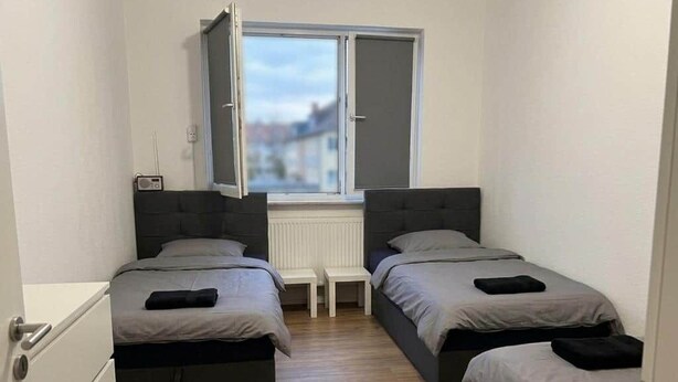 A small room with two beds, a window, and a radiator. - Mainz 3 Betten mit Parkplatz (Mainz)