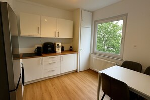 Een koelkast, een oven, kookgerei, borden en bestek