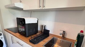 A compact kitchen with white cabinets, a stainless steel sink, a coffee machine, and a kettle. - Mainz 3 Betten mit Parkplatz (Mainz)