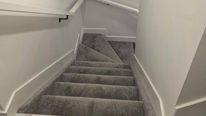 A staircase with carpeted steps and white walls. - Cozy retreat (Edmonton)