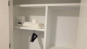 A white closet with shelves, a hanging rack, and a small white appliance. - Cozy retreat (Edmonton)