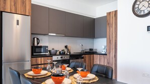 Una cocina moderna con armarios oscuros, un microondas Bosch y una cafetera.