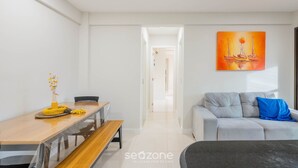 A modern living room with a dining area, a sofa, and a painting on the wall. - Complete Apt Near Stella Maris Beach Jsm0103 (Salvador)
