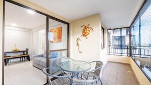 A modern living room with a glass table and chairs, a sofa, and a dining area with a bench. - Complete Apt Near Stella Maris Beach Jsm0103 (Salvador)