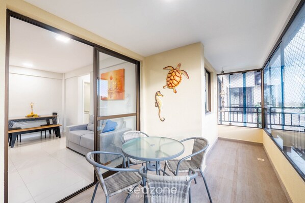 A modern living room with a glass table and chairs, a sofa, and a dining area with a bench. - Complete Apt Near Stella Maris Beach Jsm0103 (Salvador)