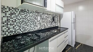 A modern kitchen with a black countertop, a gas stove, a microwave, and a refrigerator. - Complete Apt Near Stella Maris Beach Jsm0103 (Salvador)