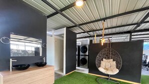 A modern bathroom with a wooden vanity, black sink, and a hanging chair. - Edificio RG33 (Medellín)