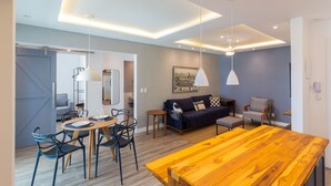 A modern living room with a wooden dining table, blue sofa, and a gray armchair. - Charming Barra 1min From the Beach Lc201b (Rio de Janeiro)