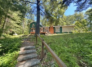Eine Holzdielen-Terrasse, die von einer Steintreppe erreichbar ist, umgeben von dichtem Wald.