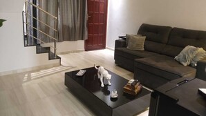 A modern living room with a dark sofa, a coffee table with a sculpture, and a staircase with a metal railing.