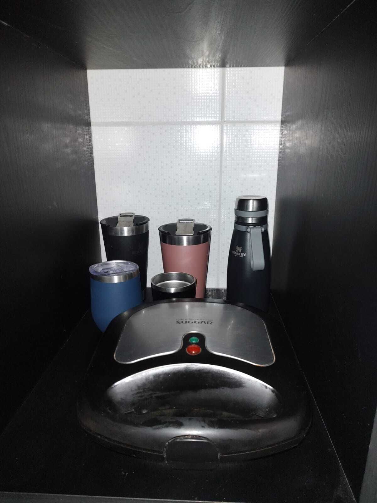 Un comptoir noir avec un évier en acier inoxydable et quatre tasses de voyage.