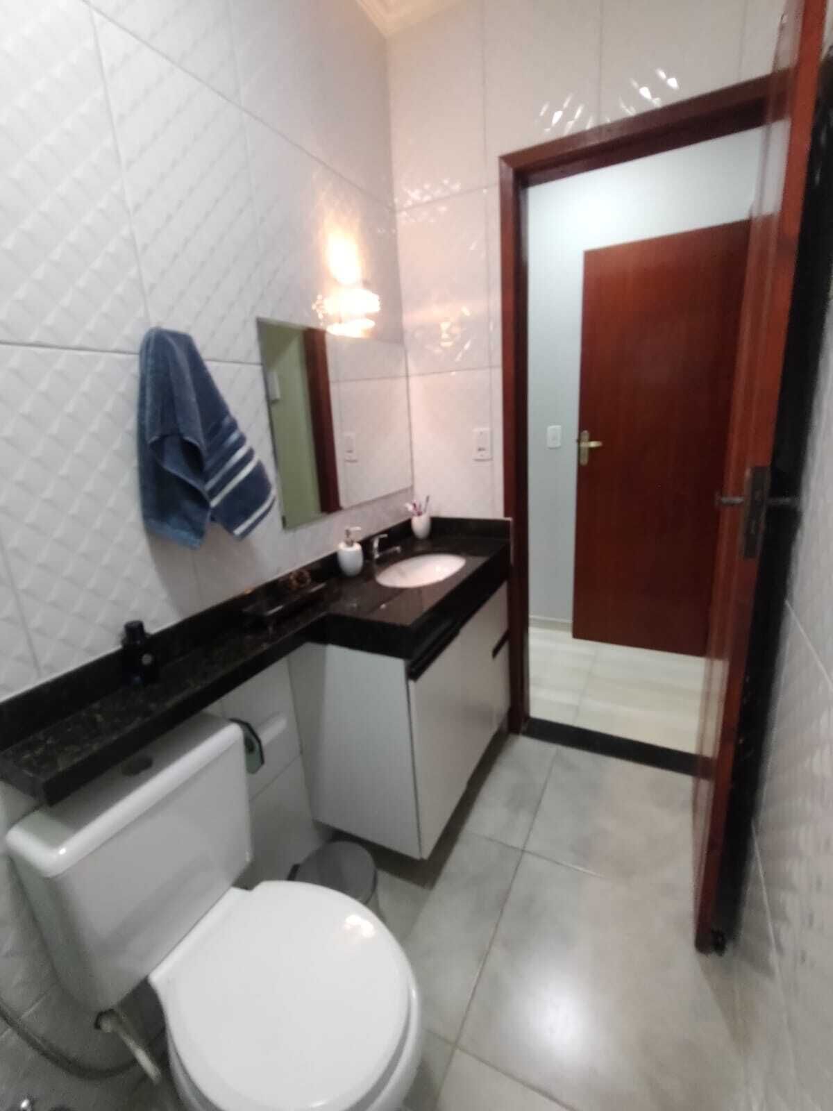 A bathroom with a white toilet, a sink with a mirror above it, and a towel hanging on the wall.