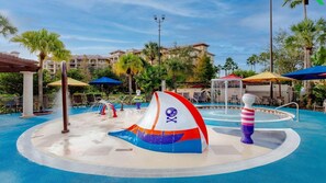 Un área de juegos acuáticos con un tobogán de temática pirata y una piscina circular con una fuente.