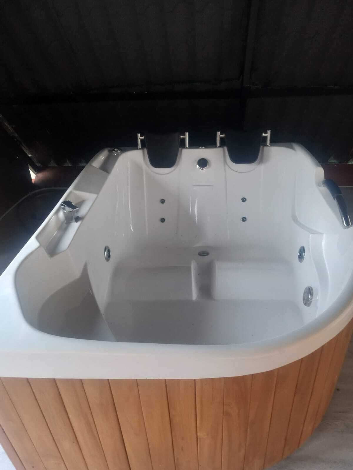 Un jacuzzi con revestimiento de madera, un panel de control y un desagüe.