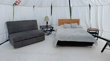 Una habitación con tienda de campaña, una cama, un sofá, dos mesitas de noche y una lámpara.