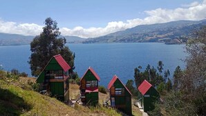 Three green cabins with red roofs overlooking a lake. - SAN ALEJO ECOHOTEL (Tota)