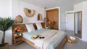 A spacious bedroom with a large bed, wooden headboard, and a small bedside table with a vase of flowers. - Anse Marcel Cove Suites St. Martin (Anse Marcel)