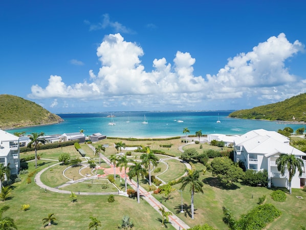 A coastal resort with a clear view of the ocean, a landscaped garden, and several buildings with a modern architectural style. - Anse Marcel Cove Suites St. Martin (Anse Marcel)