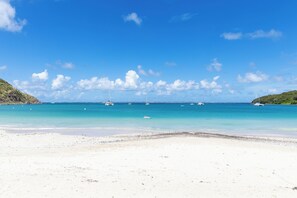 A beach with clear turquoise water, boats, and a distant shoreline. - Anse Marcel Cove Suites St. Martin (Anse Marcel)