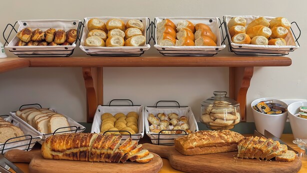 Une variété de pains et de viennoiseries présentés sur une table en bois et dans des paniers en fil de fer.