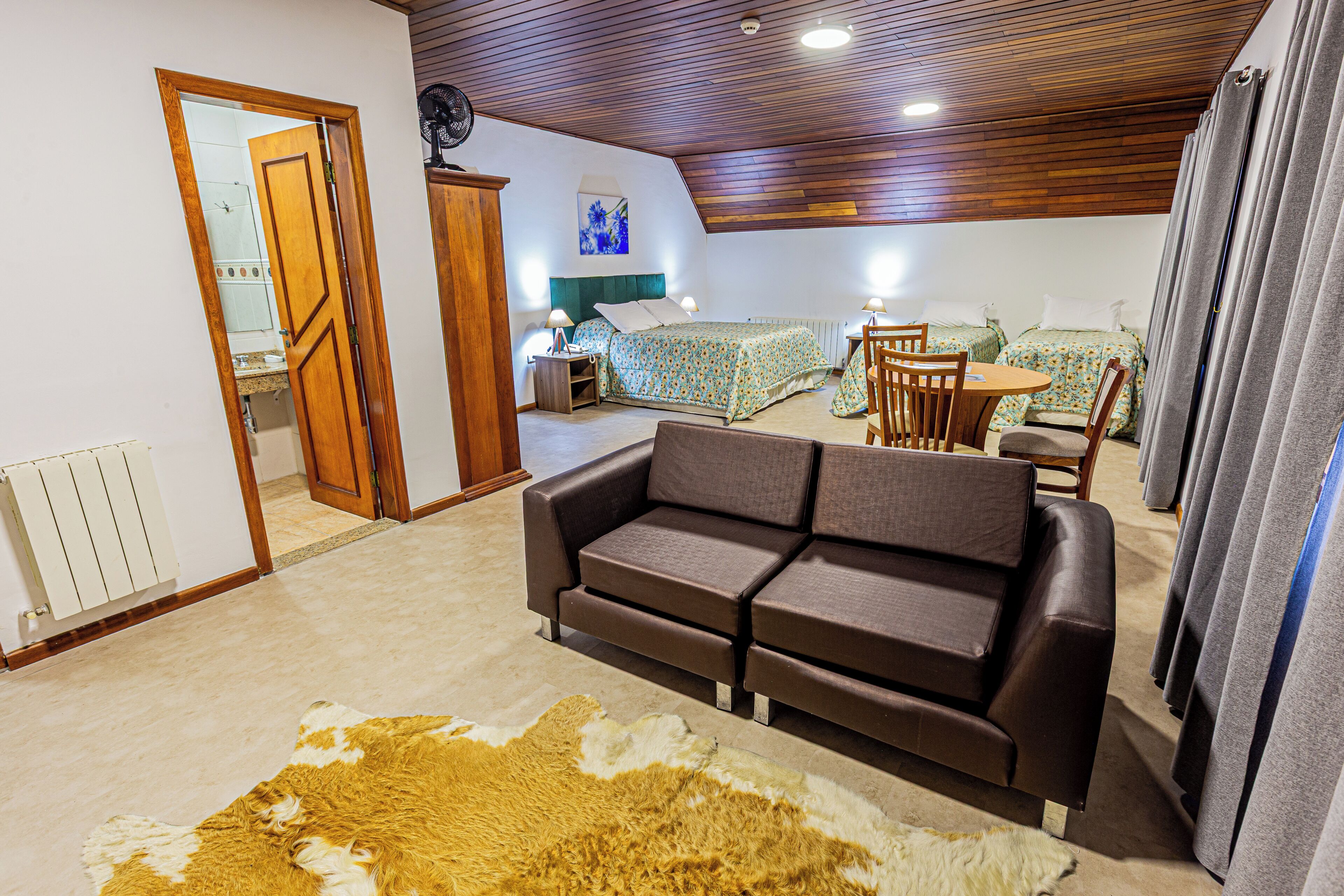 A room with a sofa, a bed with two pillows, a small table, and a chair.