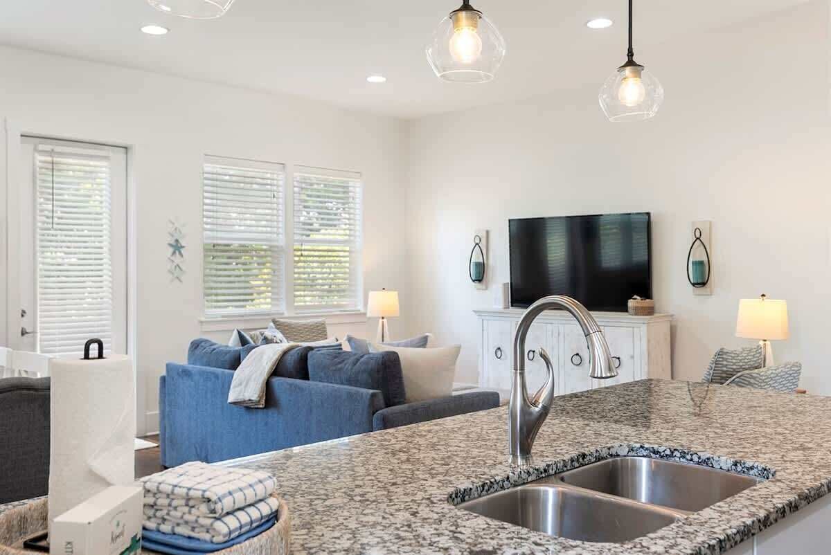 A modern kitchen with granite countertops, stainless steel sink, and pendant lighting.