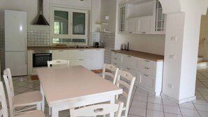 A kitchen with white cabinets, a tiled backsplash, a wooden ceiling, and a dining area with a table and chairs.