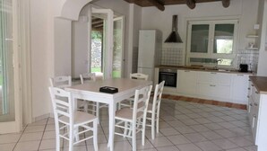 A kitchen with white cabinets, a tiled floor, and a dining area with a table and chairs.