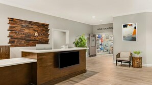Un espace d’accueil avec un comptoir de réception en bois, un téléviseur à écran plat et un panneau publicitaire pour un magasin de produits de spa, fixé au mur.
