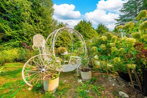 A garden with a decorative metal archway, a white metal bench, and potted plants.