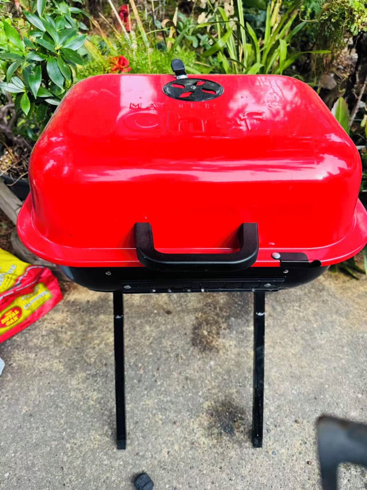 A red barbecue grill on a portable stand.