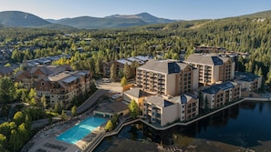Un resort con varias edificaciones, una piscina y un lago.