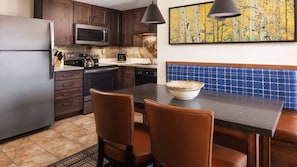 Una cocina con armarios de madera oscura, electrodomésticos de acero inoxidable, un banco de azulejos azules y un bol en la encimera.