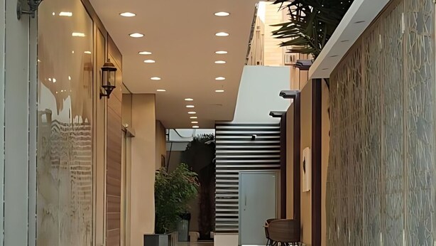 Un pasillo moderno con piso pulido, iluminación empotrada y paredes combinando elementos decorativos y lisos.