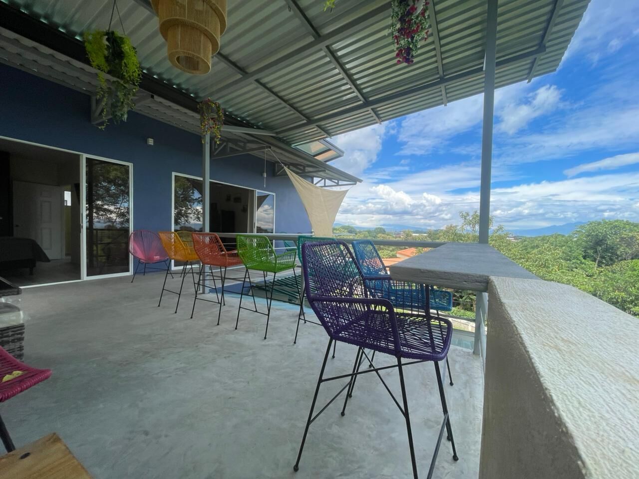 Un patio al aire libre con zona de estar cubierta, vistas al paisaje y un edificio con grandes ventanales.