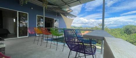 Un patio al aire libre con zona de estar cubierta, vistas al paisaje y un edificio con grandes ventanales.