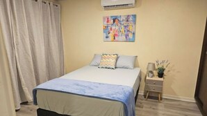 Une chambre à coucher avec un lit, une table de chevet, une lampe et un tableau au mur.