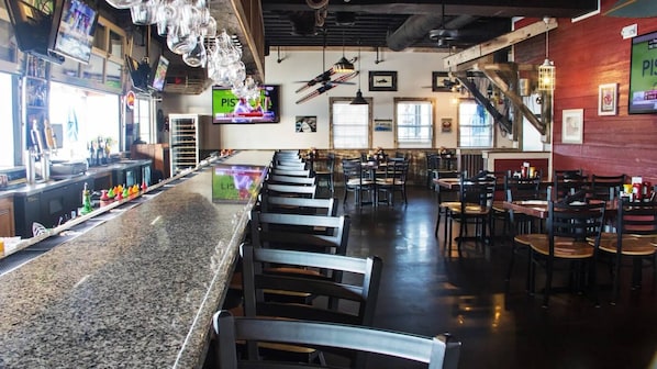 A bar area with a counter, bar stools, and a television screen.