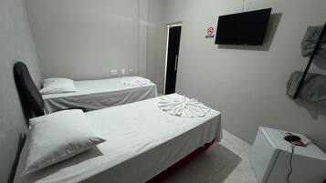 Habitación de hotel con dos camas, televisión y escritorio con computadora.